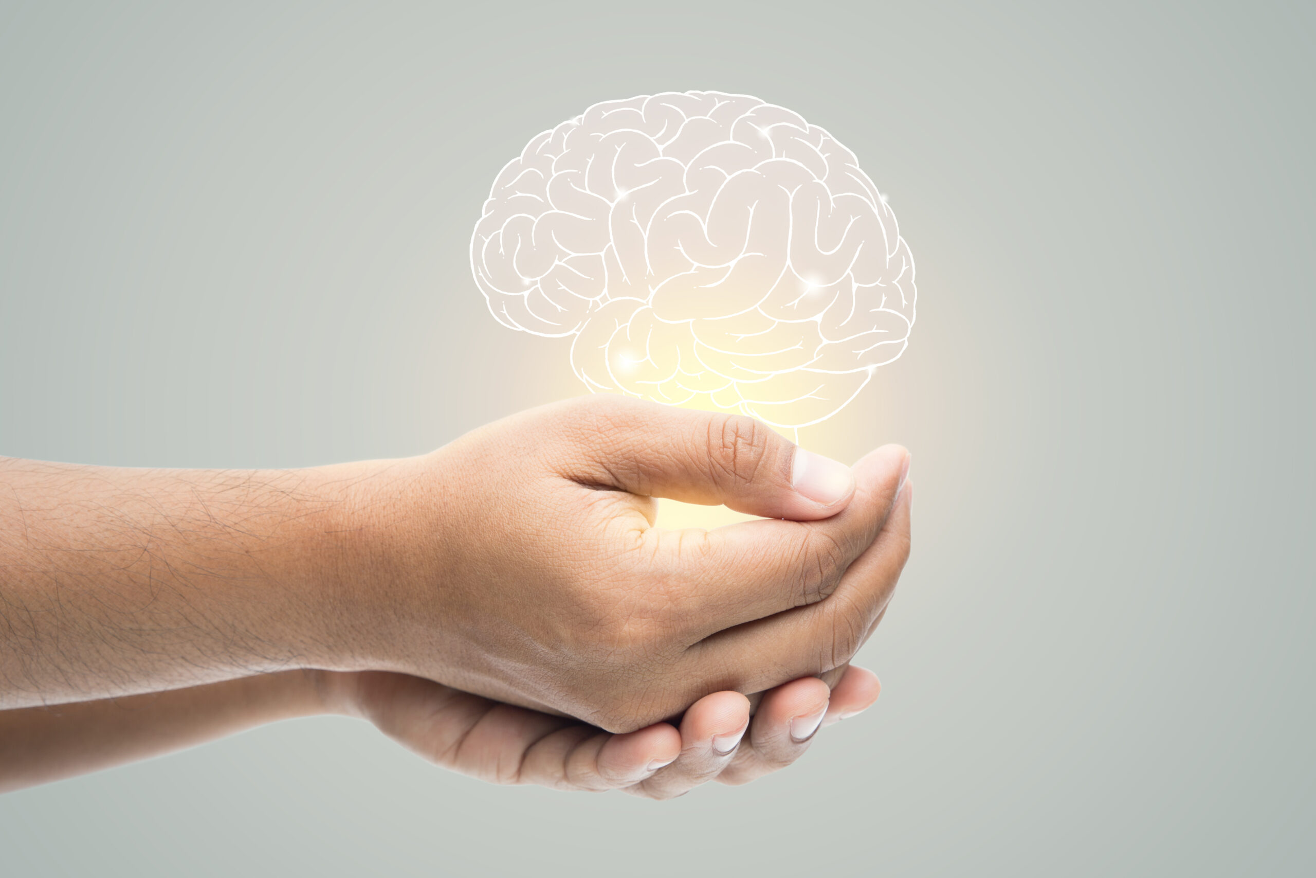 Man holding brain illustration against gray wall background. Concept with mental health protection and care.